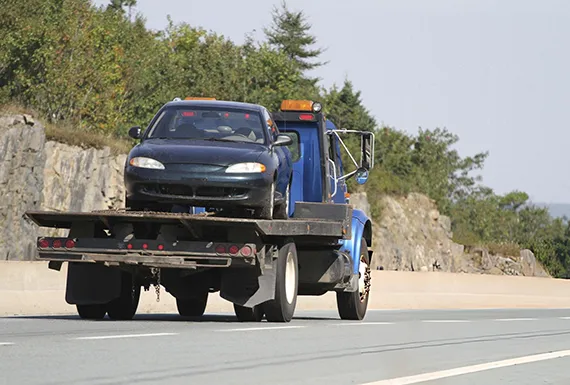 A tow truck transporting a car on a flatbed truck for fast cash for junk vans in Dacula GA.